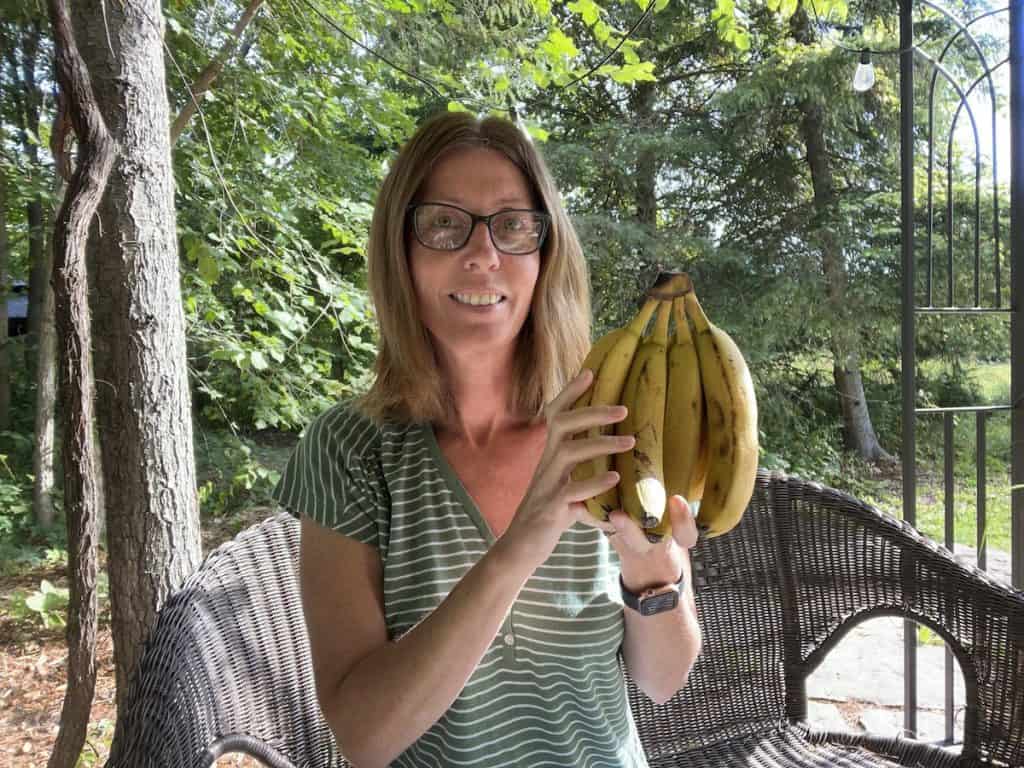 Woman sitting outside holding a bunch of bananas